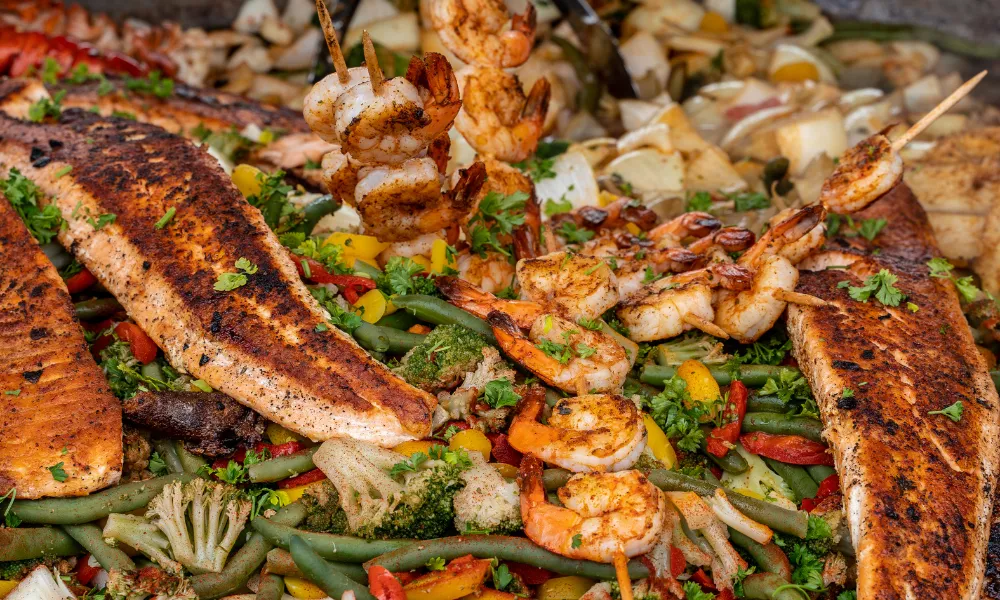 close up view of a seafood platter with vegetables, salmon, scallops, and shrimp